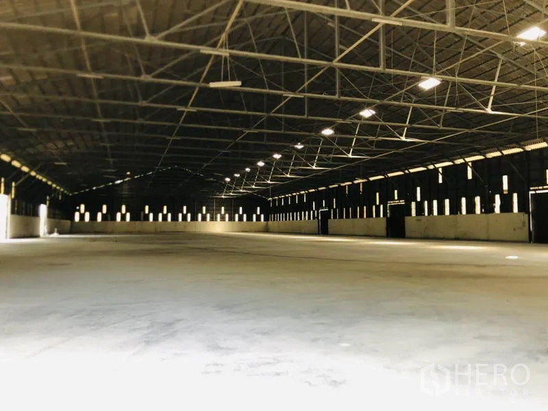 Warehouse for rent in Nonthaburi - Open clear-span warehouse floor with high roof and strip windows.
