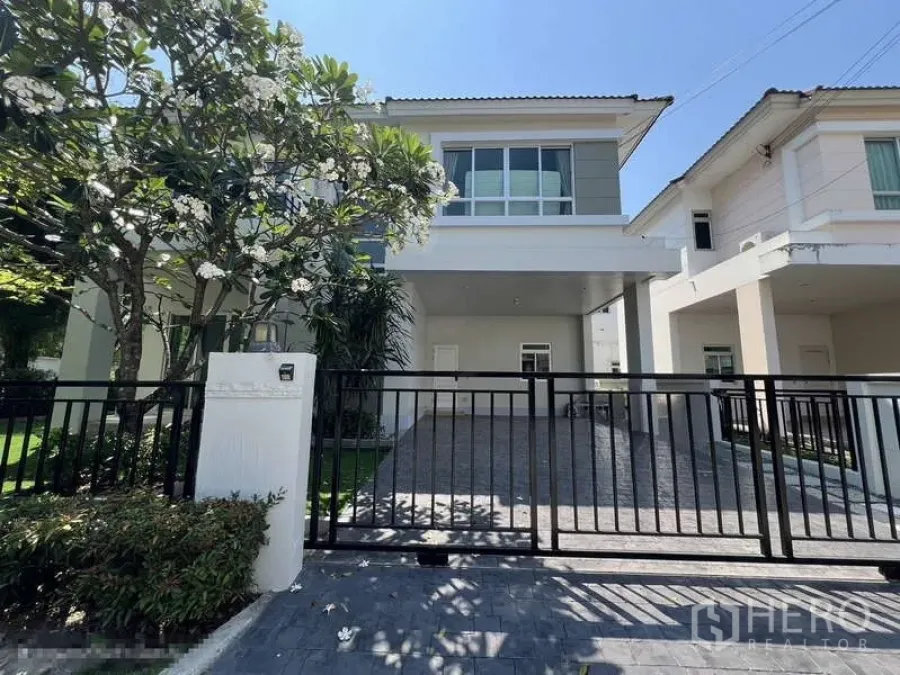 独立式住宅 出租在Saphan Sung, Bangkok - 现代两层独栋别墅正面，黑色大门、车道与鸡蛋花树