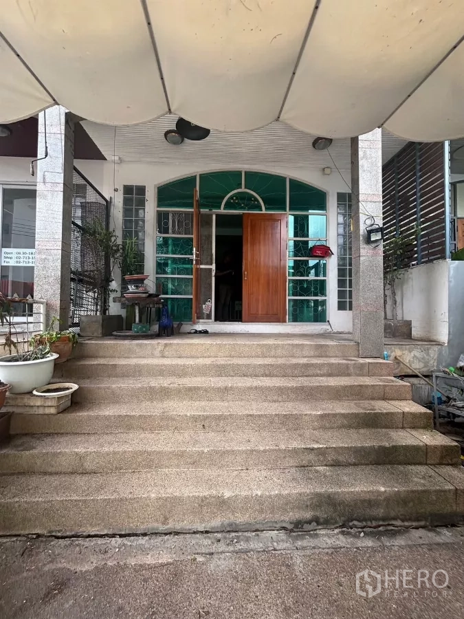 店屋 出租在Watthana, Bangkok - 正面宽阔台阶通向拱形玻璃入口，配实木大门。