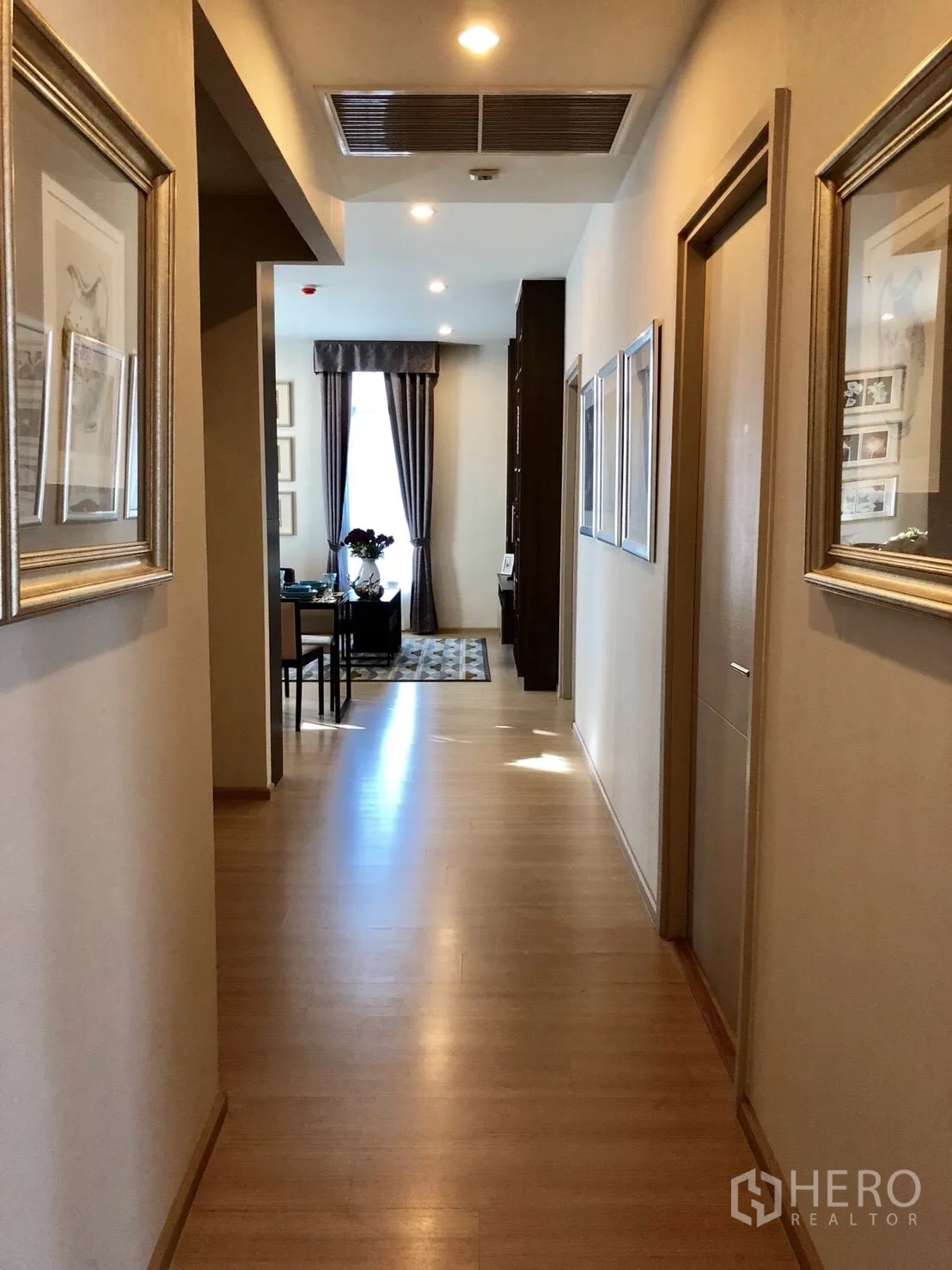 Condominium for rent or sale in Huai Khwang, Bangkok - Long hallway with wood floors leading to the sunny living and dining area.
