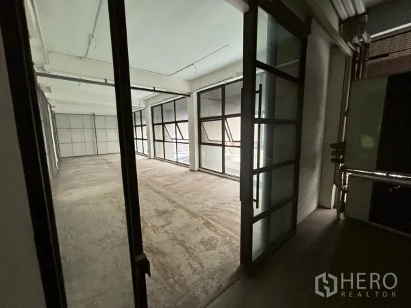 พื้นที่ขายปลีก ให้เช่า - มุมมองจากประตูกระจกทางเข้าไปยังพื้นที่โล่งโปร่ง มีหน้าต่างบานกว้างและฝ้าเพดานเดินท่อโชว์