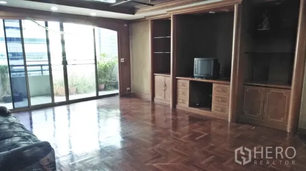 Condominium for sale in Watthana, Bangkok - Large lounge with built-in wooden cabinetry and glass doors to a terrace.