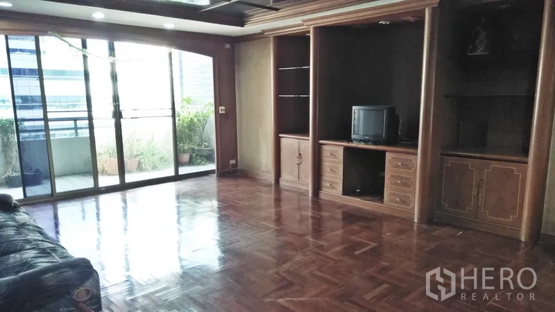 Condominium for sale in Watthana, Bangkok - Large lounge with built-in wooden cabinetry and glass doors to a terrace.