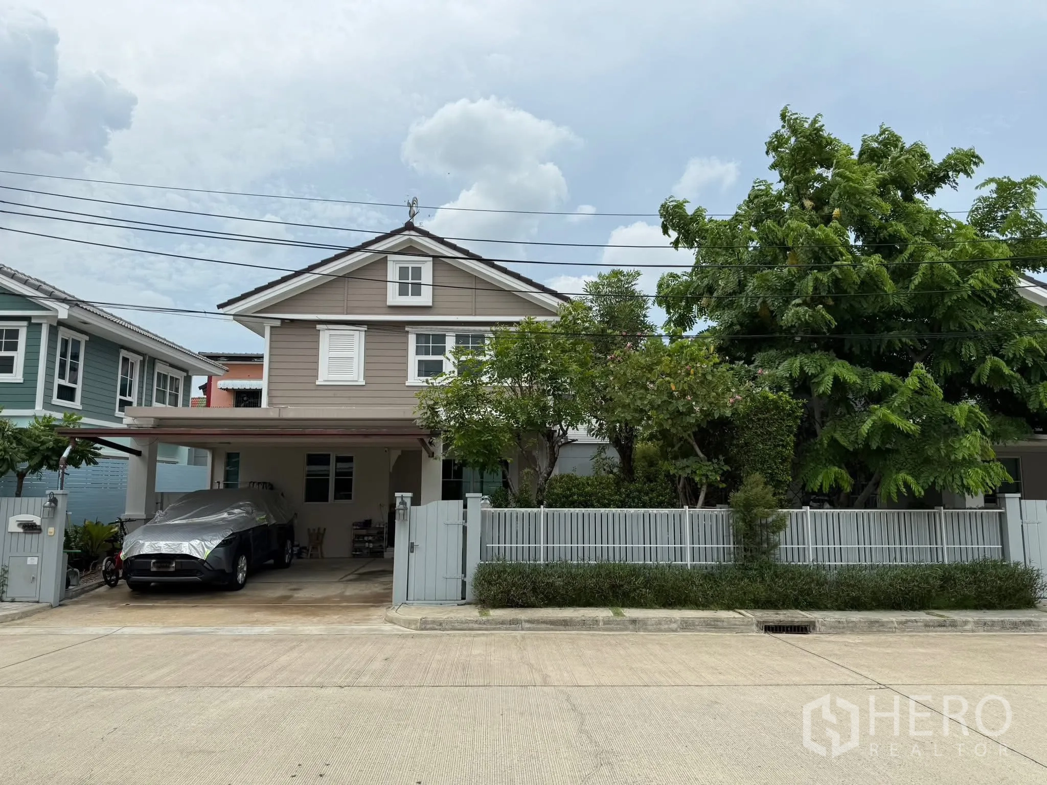 Townhouse for rent or sale in Sai Mai, Bangkok - Two-storey townhouse exterior with covered carport, front fence and mature trees in Sai Mai, Bangkok.
