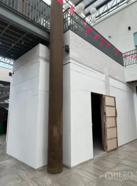 零售空间 出租在Khlong Toei, Bangkok - 白色墙面的拐角铺面，敞开门口，上方可见夹层与彩旗。