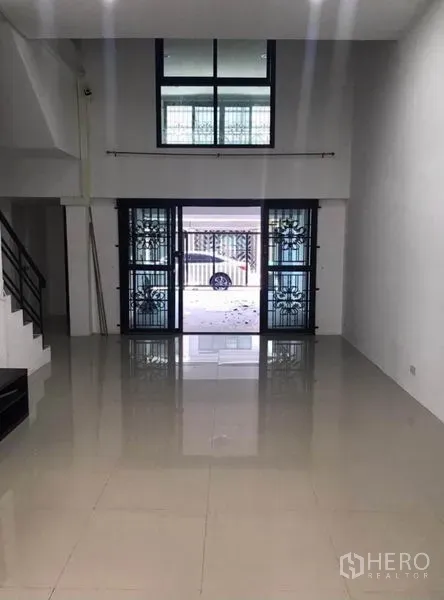 Townhouse for rent in Wang Thonglang, Bangkok - Open-plan living area with high ceiling and sliding glass doors to the carport.