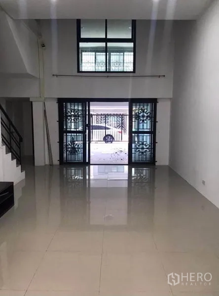 Townhouse for rent in Wang Thonglang, Bangkok - Open-plan living area with high ceiling and sliding glass doors to the carport.
