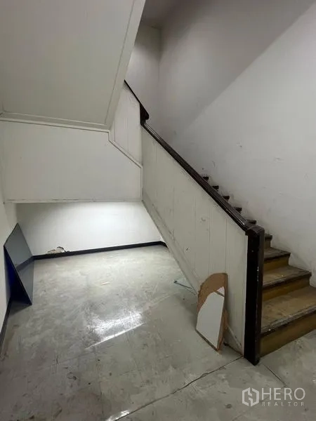 Shophouse for rent in Samphanthawong, Bangkok - Stair landing showing wooden stairs and white wall paneling.