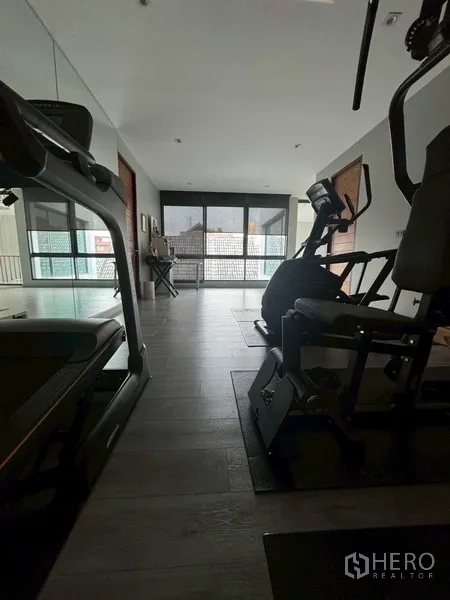 Semi-detached House for rent in Watthana, Bangkok - Home gym room with treadmill, elliptical machine, and large windows.