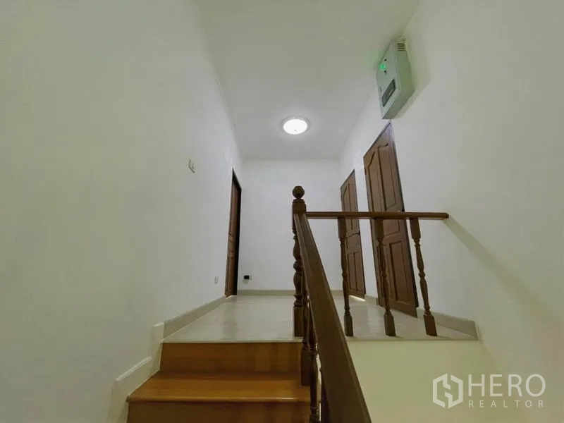 บ้าน ให้เช่าในSuan Luang, Bangkok - โถงชั้นบนพร้อมประตูไม้สู่ห้องต่างๆ และไฟเพดานนุ่มนวล.