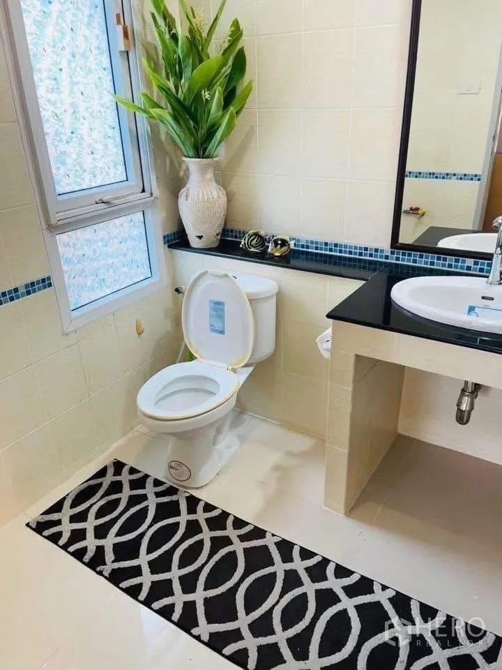 独立式住宅 出租或出售在Lam Luk Ka, Pathum Thani - 整洁瓷砖浴室，盥洗台、镜子与窗户旁坐便器。