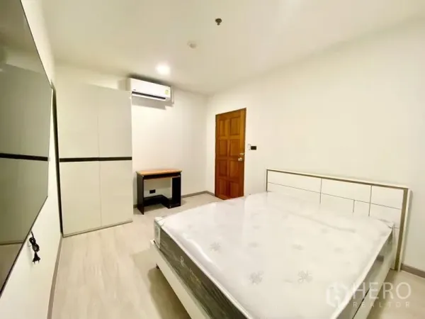 คอนโด ให้เช่า - ห้องนอนที่สองมีตู้เสื้อผ้า โต๊ะทำงาน ประตูไม้ และเครื่องปรับอากาศ