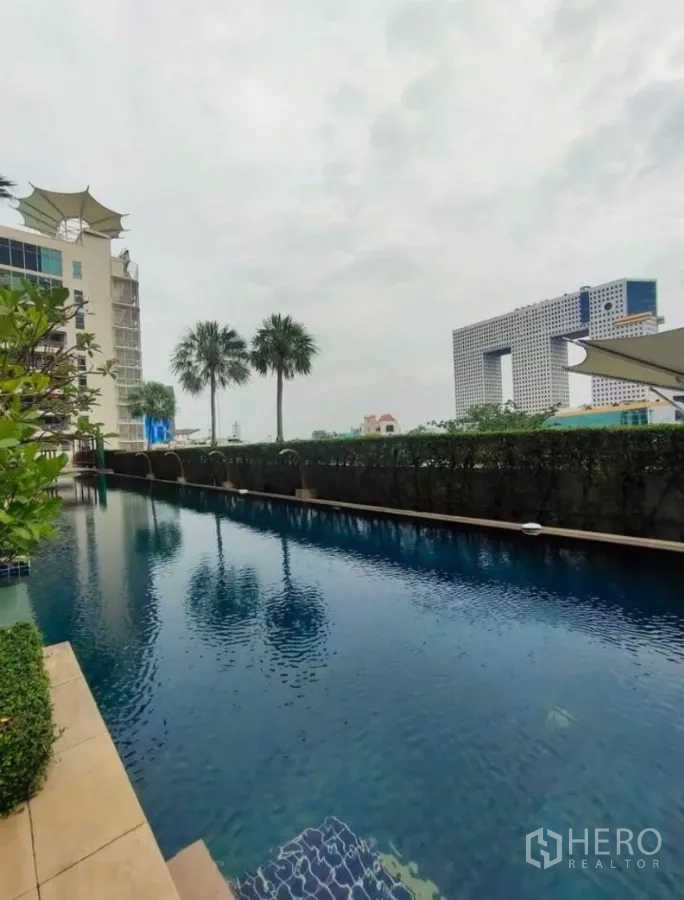 Condominium for rent in Chatuchak, Bangkok - Outdoor swimming pool lined with palm trees and city view.