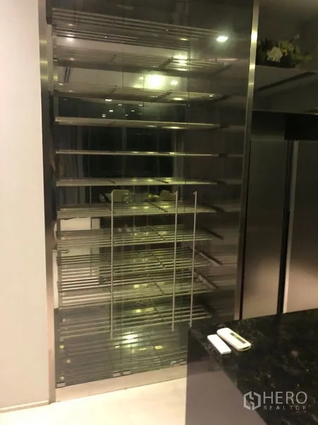 独立式住宅 出租在Wang Thonglang, Bangkok - 厨房区的玻璃门不锈钢层架，旁为深色石材台面。