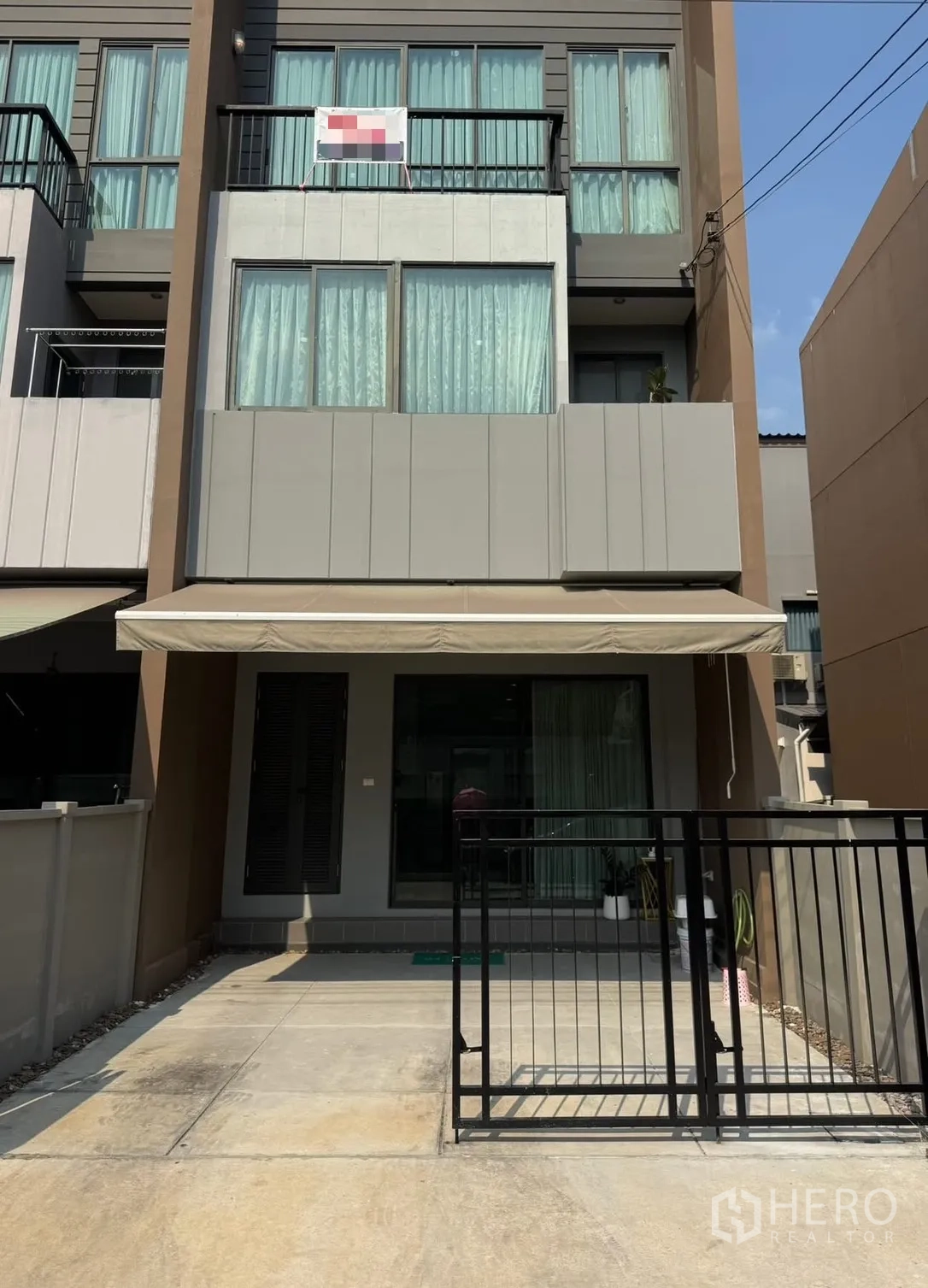 Townhouse for rent in Saphan Sung, Bangkok - Three-storey townhouse exterior with balconies, awning and front gate.