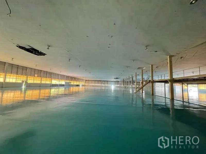 Factory for rent in Khlong Toei, Bangkok - Lower-level production area with epoxy flooring, support columns and a service staircase.