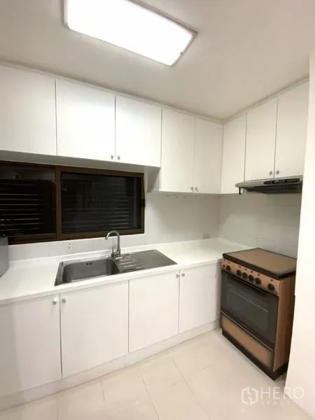 คอนโด ให้เช่าในWatthana, Bangkok - ครัวปิดโทนสีขาว ตู้บน-ล่าง อ่างล้างจานใตัหน้าต่าง เตาอบและเครื่องดูดควัน