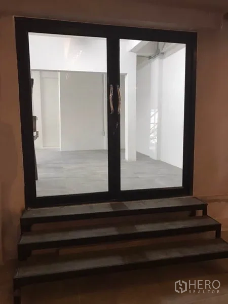Office Space for rent in Watthana, Bangkok - Black-framed double glass doors with short steps leading into a bright office area.
