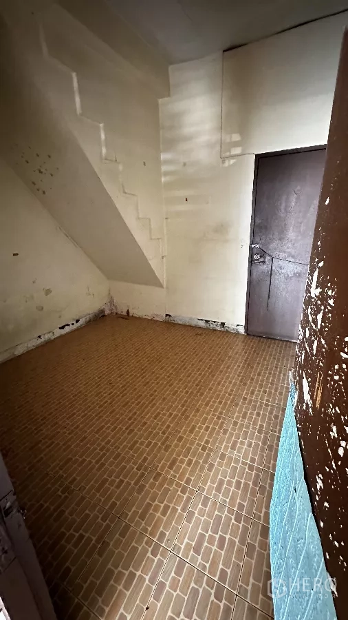 Shophouse for rent in Chatuchak, Bangkok - Compact room beneath the staircase with brown floor tiles and a solid door, suitable for storage or back office.