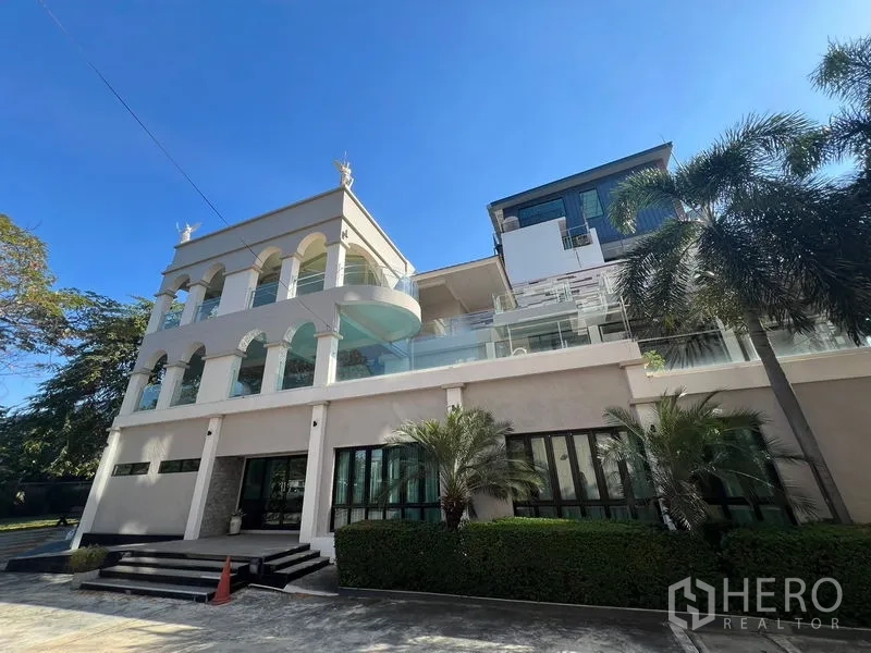 店屋 出租在Suan Luang, Bangkok - 拱券与玻璃阳台并列的店屋外立面，门前有棕榈与景观。