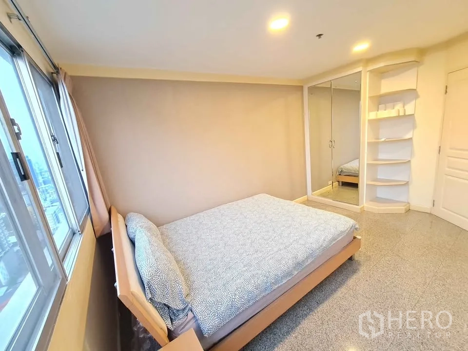 Condominium for rent in Khlong Toei, Bangkok - Primary bedroom showcasing city views through long windows and soft drapes.