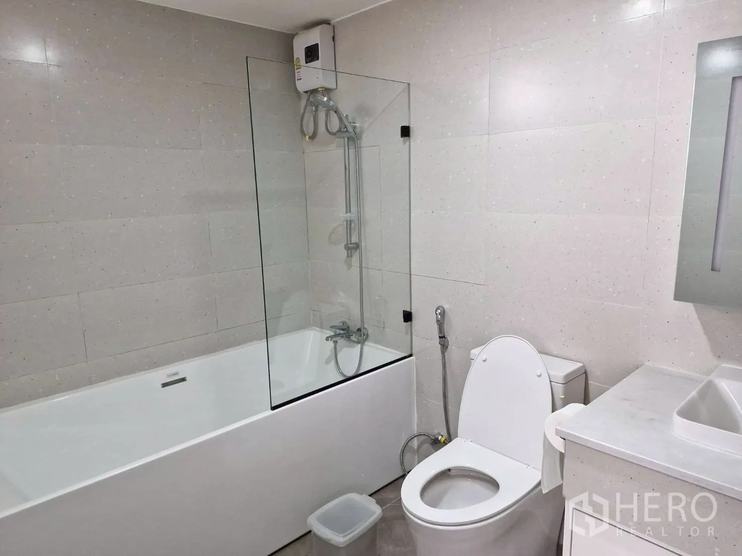Condominium for rent in Khlong Toei, Bangkok - Bathroom featuring a bathtub with shower screen, toilet and vanity with mirror.