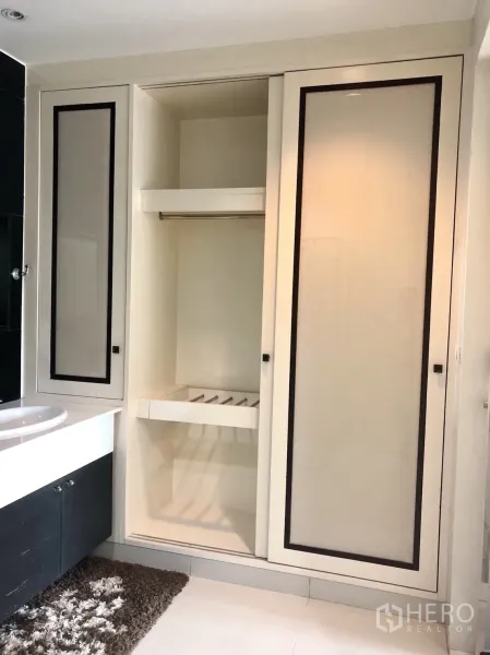 公寓 出租在Pathum Wan, Bangkok - 浴室洗手台旁设大容量嵌入式滑门衣柜，白色地砖。