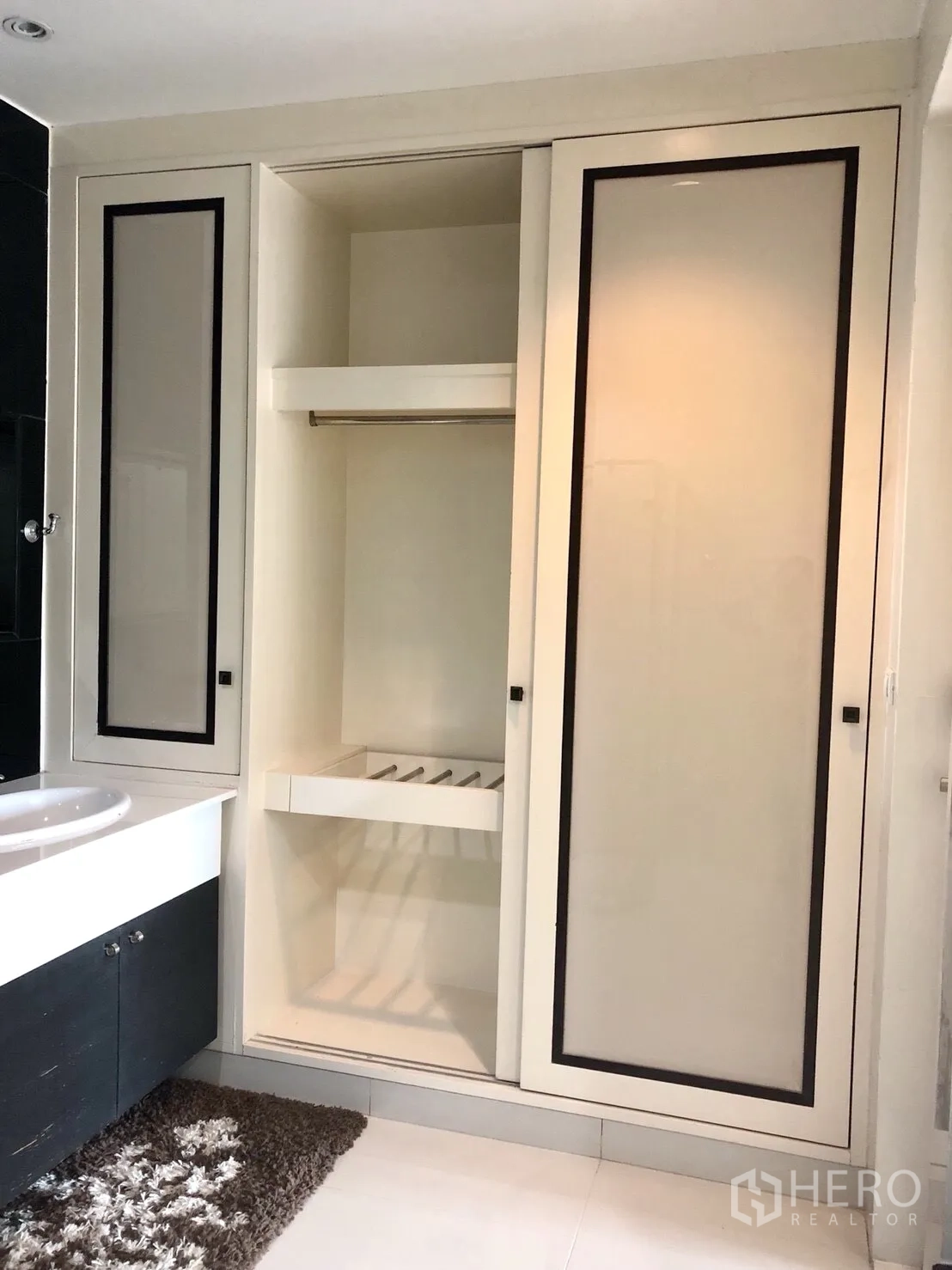 公寓 出租在Pathum Wan, Bangkok - 浴室洗手台旁设大容量嵌入式滑门衣柜，白色地砖。
