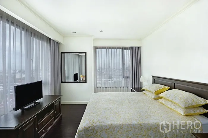 Condominium for rent in Khlong San, Bangkok - Master bedroom with king bed, TV console and two large windows with city views.
