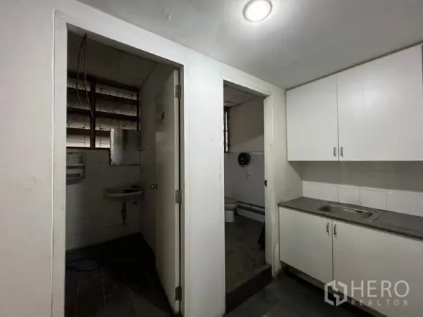 Warehouse for rent in Suan Luang, Bangkok - Utility corner with kitchenette cabinetry, sink, and two separate restrooms inside the warehouse.