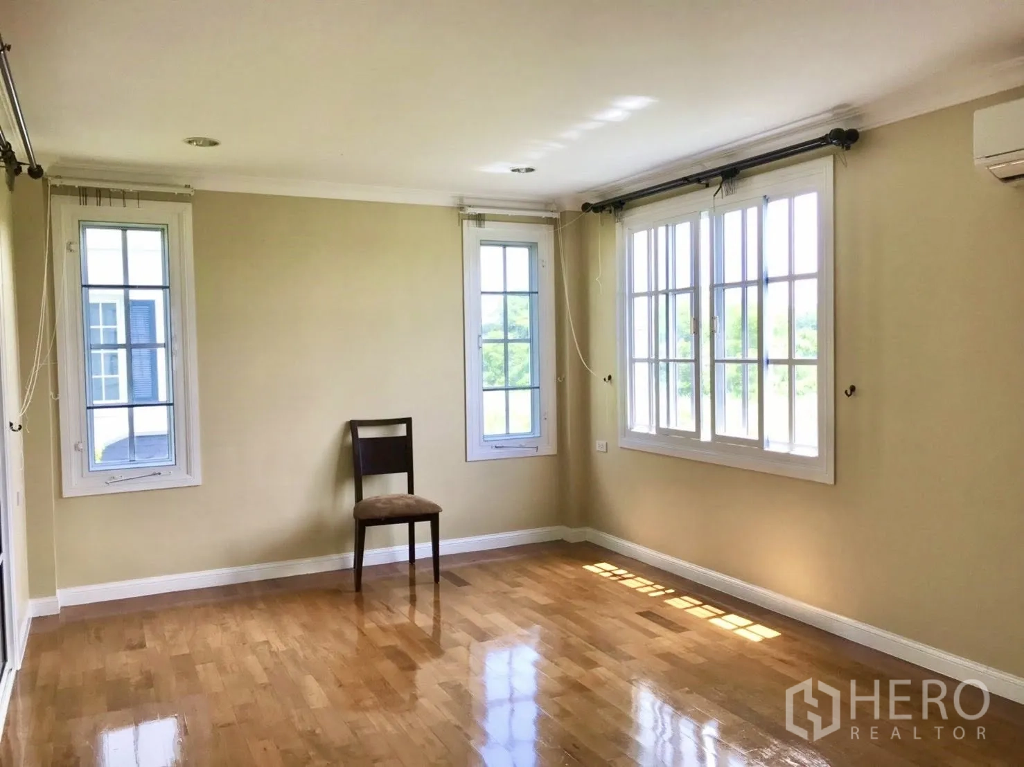 Detached House for rent in Mueang Samut Prakan, Samut Prakan - Sunlit empty room with multiple windows and an air conditioner.