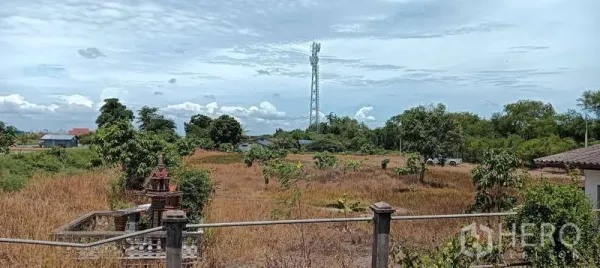 Land for sale in Bang Sao Thong, Samut Prakan - Expansive industrial-zoned land in Bang Bo with grassy field, perimeter fence and a telecom tower under blue sky.