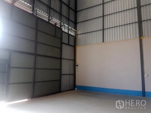 货栈 出租在Prawet, Bangkok - 高挑仓库内部，金属波纹墙体，大型推拉门与混凝土地面。