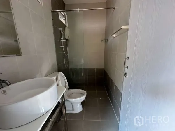 Home Office for rent in Chatuchak, Bangkok - Tiled bathroom with a basin, toilet and walk-in shower with water heater.