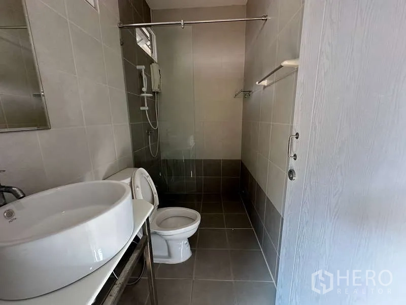 Home Office for rent in Chatuchak, Bangkok - Tiled bathroom with a basin, toilet and walk-in shower with water heater.