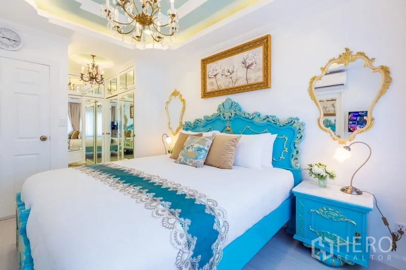 联排别墅 出租在Lat Phrao, Bangkok - 次卧配蒂凡尼蓝巴洛克床、镜面衣柜与吊灯，灯光柔和。
