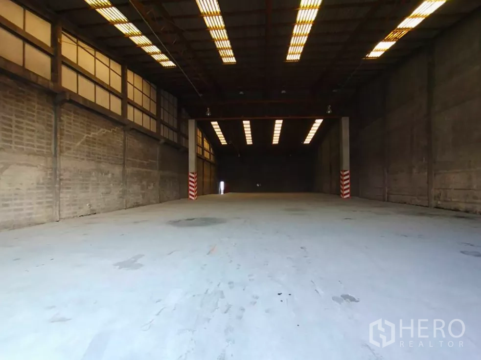 工厂 出租在Phra Pradaeng, Samut Prakan - 宽敞厂房内景，挑高空间、条形照明，重载混凝土地面适合叉车作业。