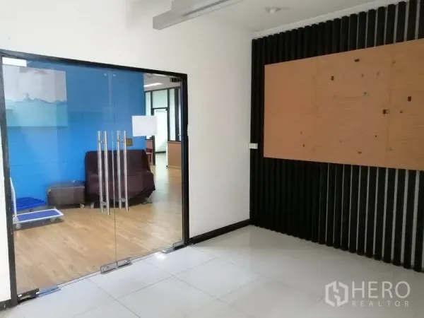 Office Space for rent in Bueng Kum, Bangkok - Glass double doors open to a wood‑floor office with a blue feature wall and seating area.