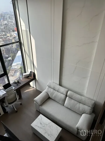 公寓 出租在Bang Rak, Bangkok - 挑高客厅，落地窗、灰色沙发与大理石茶几，欣赏城市景观。