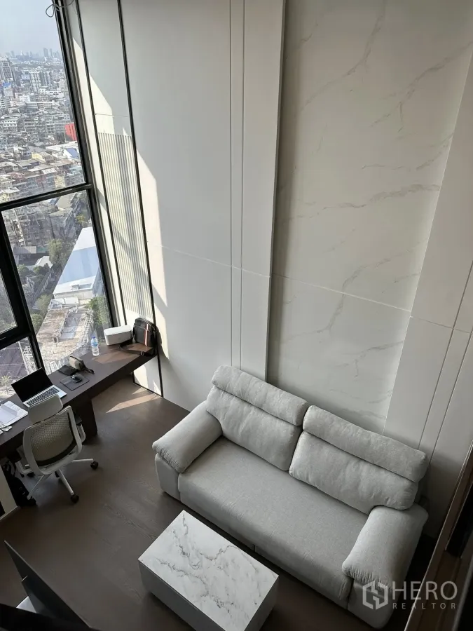 公寓 出租在Bang Rak, Bangkok - 挑高客厅，落地窗、灰色沙发与大理石茶几，欣赏城市景观。