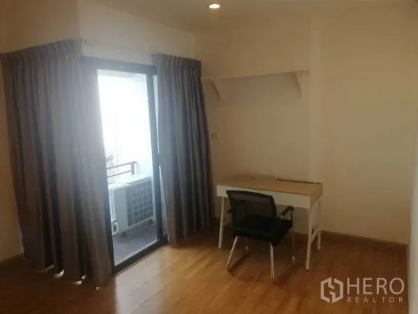 Townhouse for rent in Wang Thonglang, Bangkok - Compact study corner with desk and chair beside a sliding glass door to the balcony.