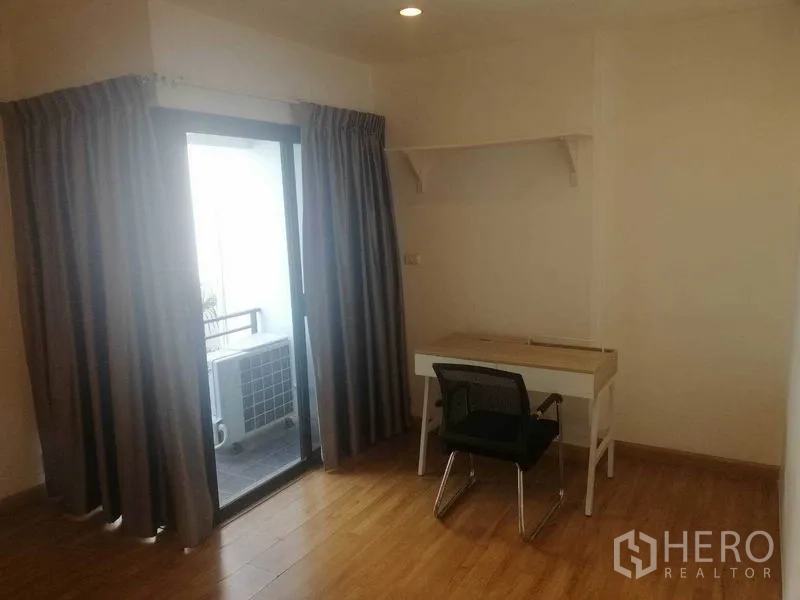 Townhouse for rent in Wang Thonglang, Bangkok - Compact study corner with desk and chair beside a sliding glass door to the balcony.