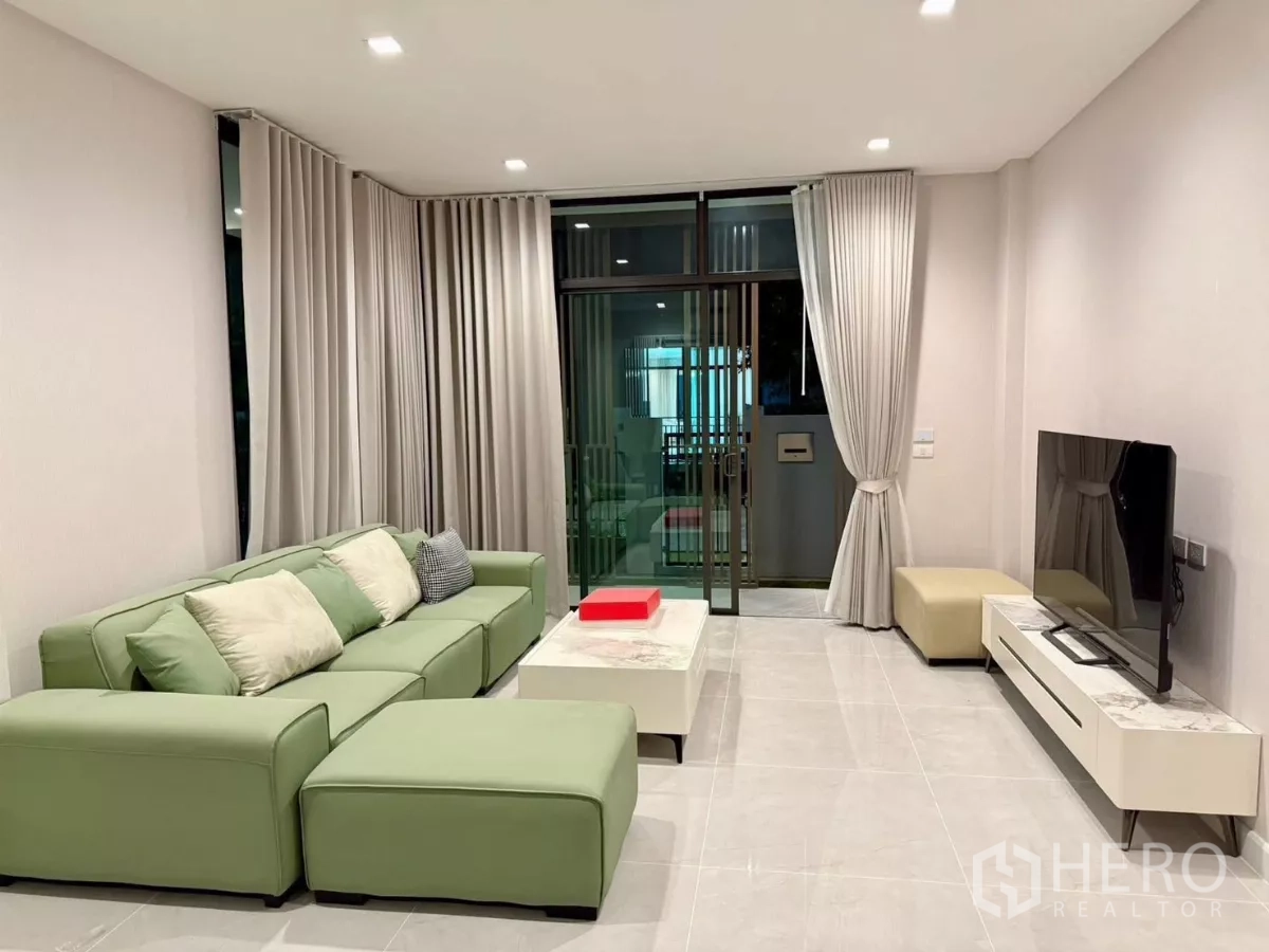 Detached House for rent in Bang Phli, Samut Prakan - Living area with floor-to-ceiling curtains and sliding glass doors to the patio.