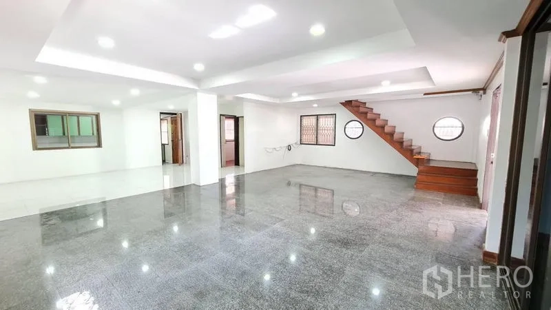 独立式住宅 出租在Lat Phrao, Bangkok - 宽敞客厅视角，楼梯、大窗与光亮地砖一览。