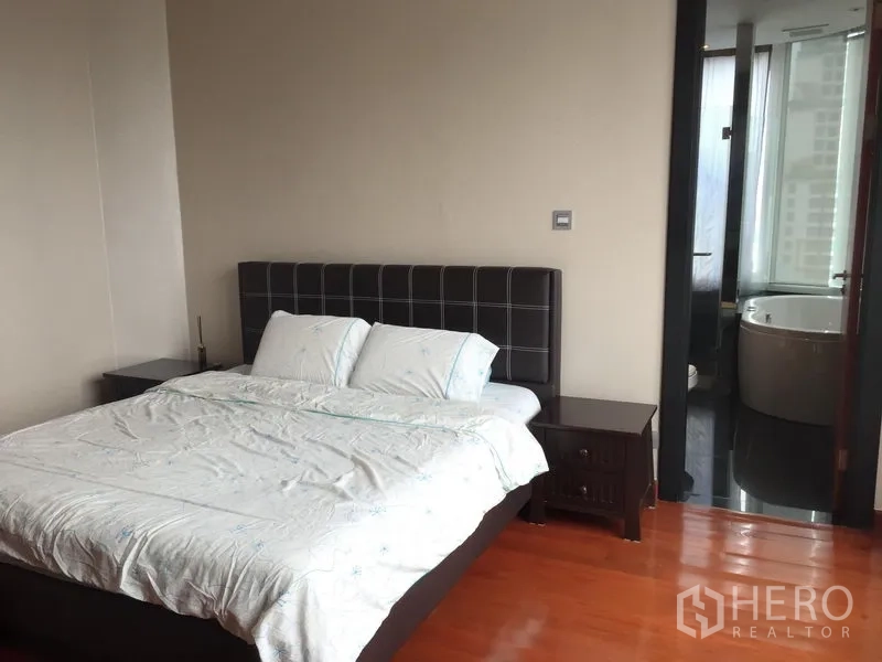 Condominium for rent or sale in Bang Rak, Bangkok - Master bedroom with king bed and doorway to an en-suite bathroom.