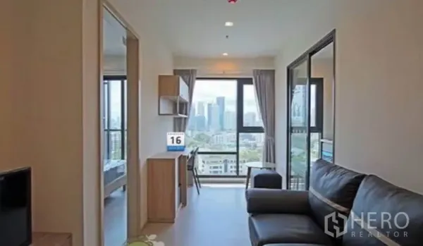 Condominium for rent in Khlong Toei, Bangkok - Open-plan living area facing floor-to-ceiling windows with adjoining bedroom.