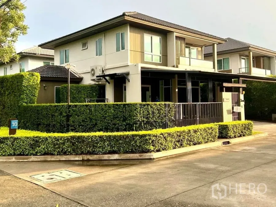 Townhouse for sale in Bang Khae, Bangkok - Corner-plot townhouse exterior with neat hedges and wide internal road in a gated community.