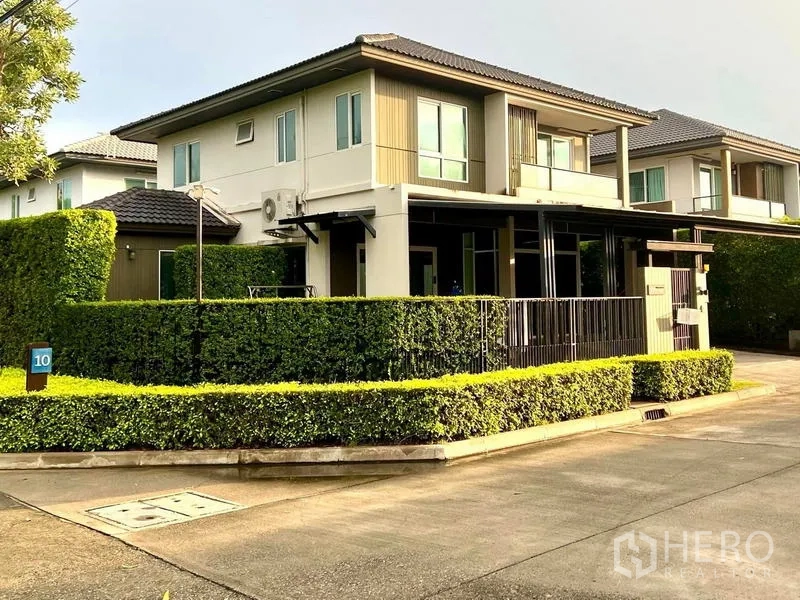 Townhouse for sale in Bang Khae, Bangkok - Corner-plot townhouse exterior with neat hedges and wide internal road in a gated community.