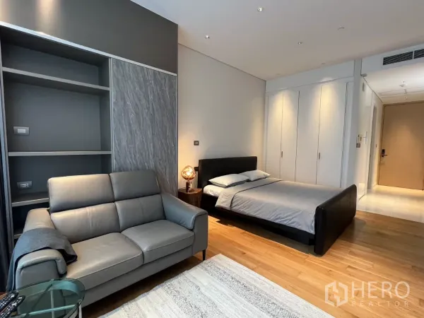คอนโด ให้เช่าในPathum Wan, Bangkok - พื้นที่พักผ่อนแบบเปิดโล่ง มีเตียงควีน โซฟาสีเทา พื้นไม้ และตู้เสื้อผ้าบิวต์อินเต็มความสูง