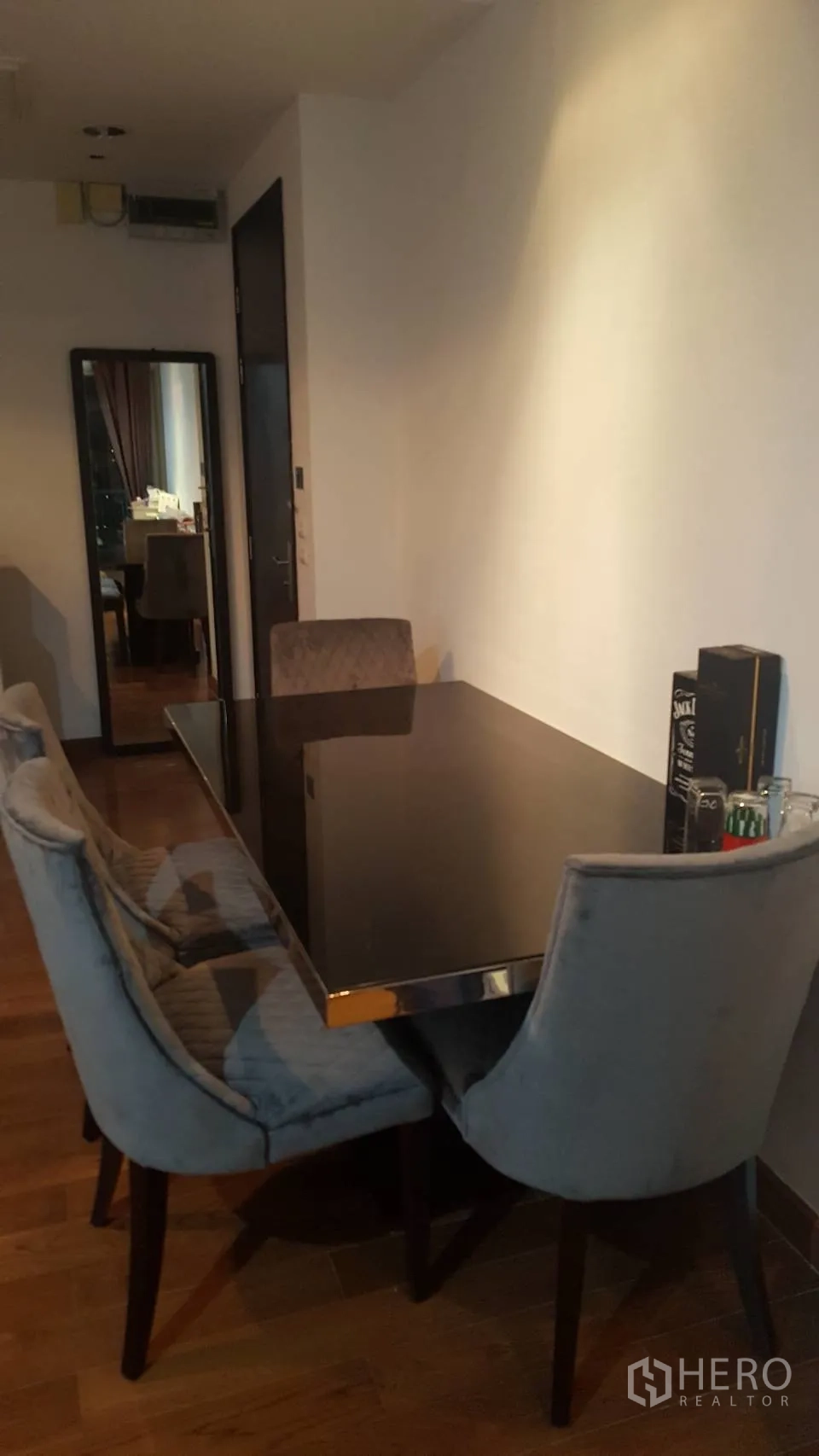 คอนโด ให้เช่าในPathum Wan, Bangkok - มุมรับประทานอาหารพร้อมโต๊ะแก้วสีดำ เก้าอี้บุผ้า และพื้นไม้ในคอนโดสมัยใหม่